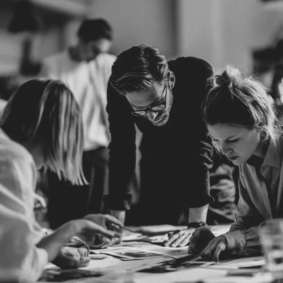 Team leaning over drafts, photos and material samples on a table